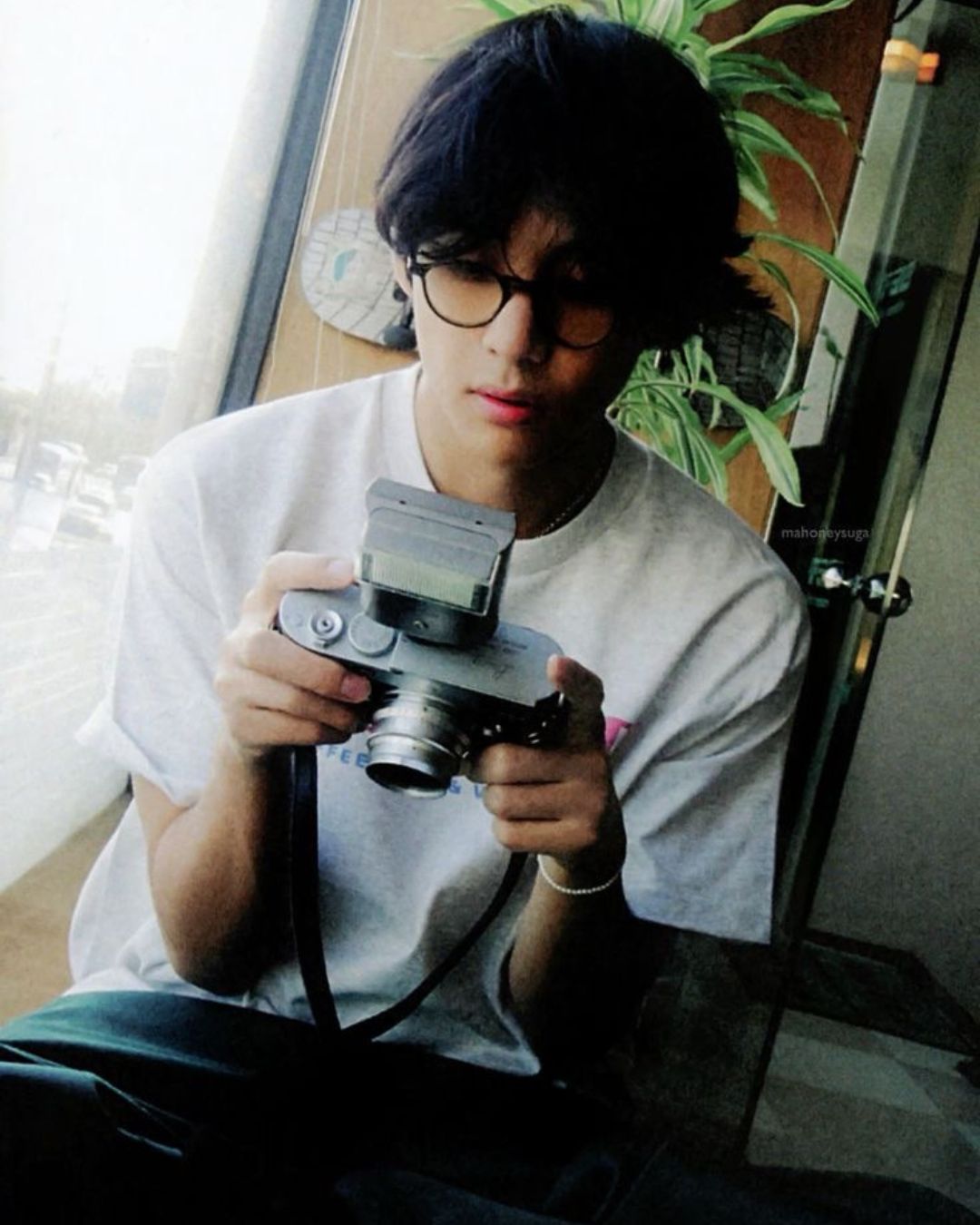 “Taehyung con cámara vintage mostrando su pasión por la fotografía”
